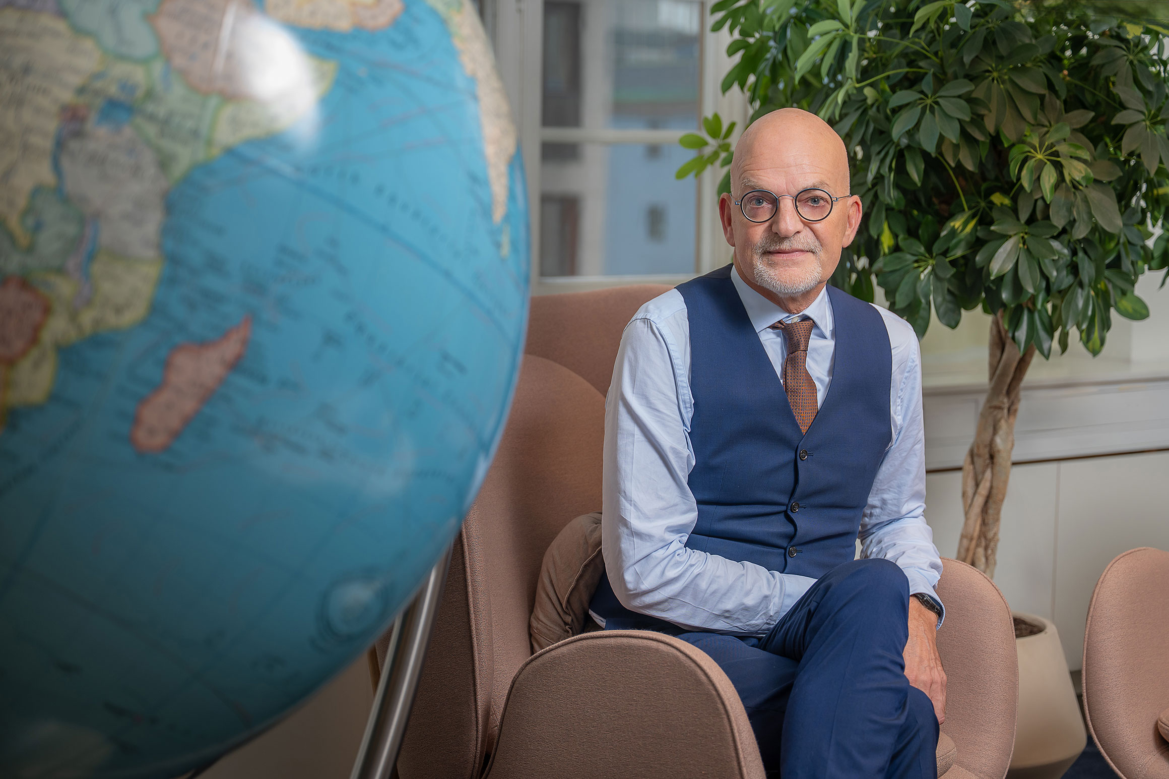 Åke Nordlander sitting in a chair next to a giant globe