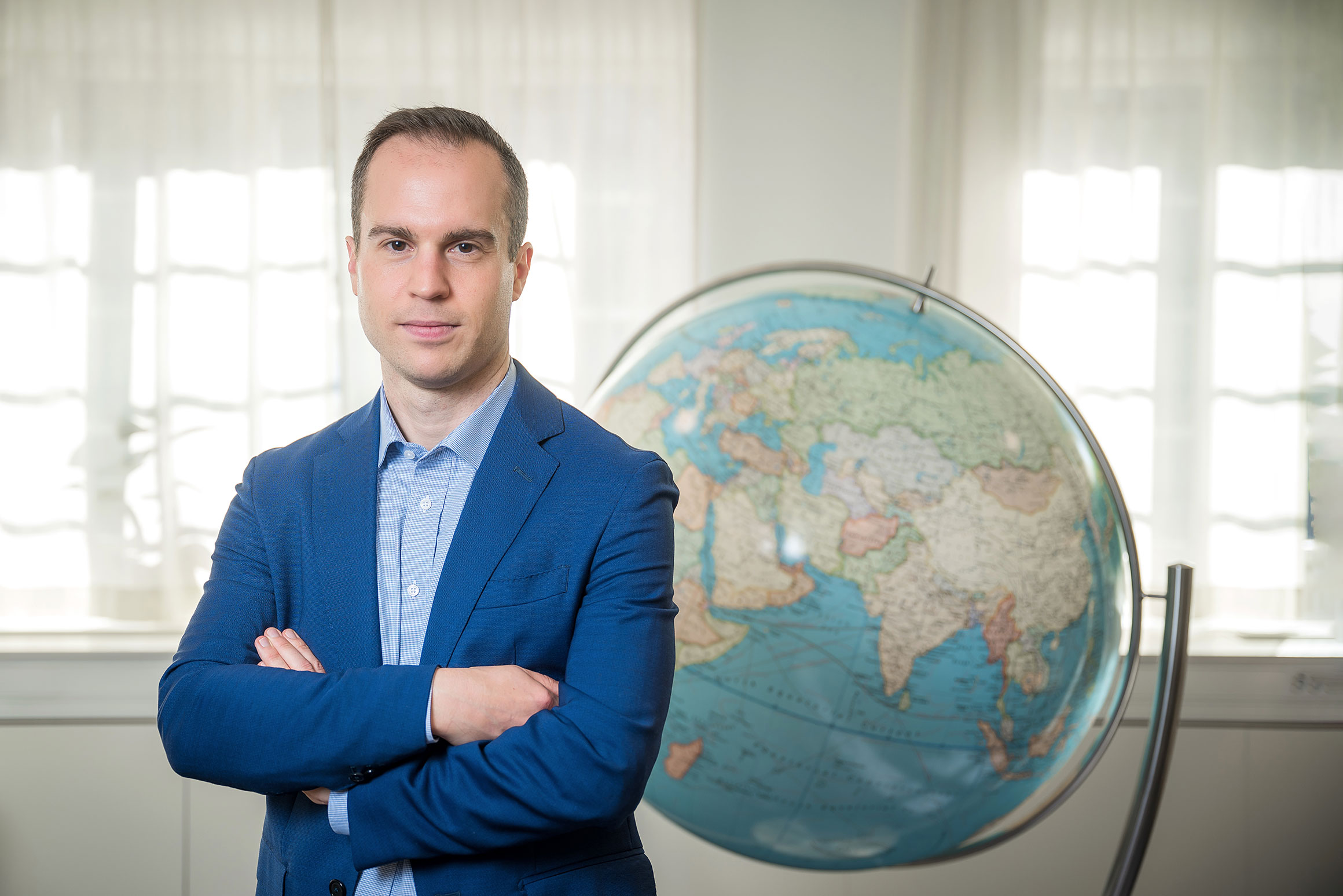 Victor Carstenius standing beside a large globe.