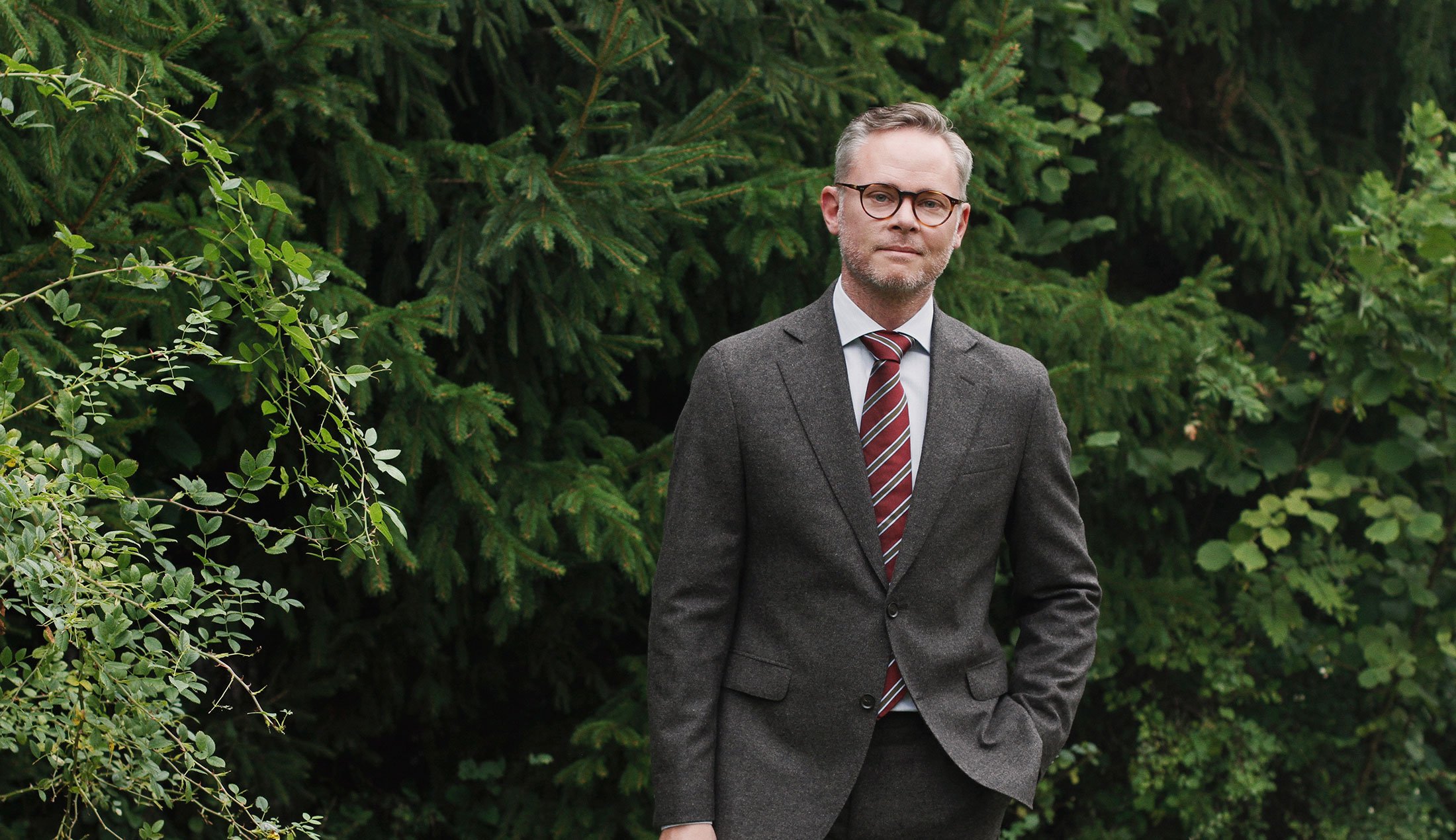 Fredrik Larsson står framför träd och buskar