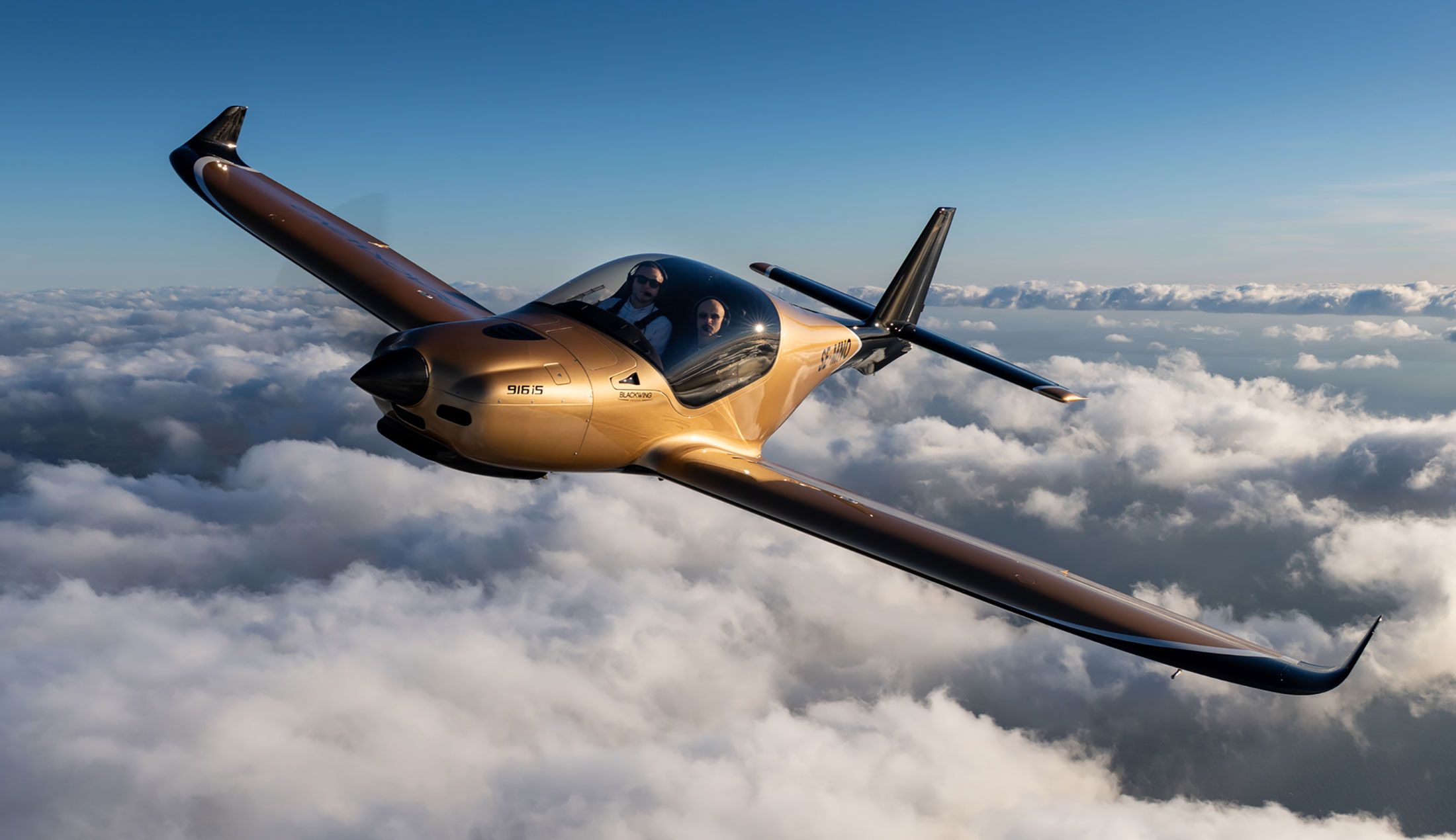 Två män syns i ett Blackwing-plan som flyger ovan molnen.