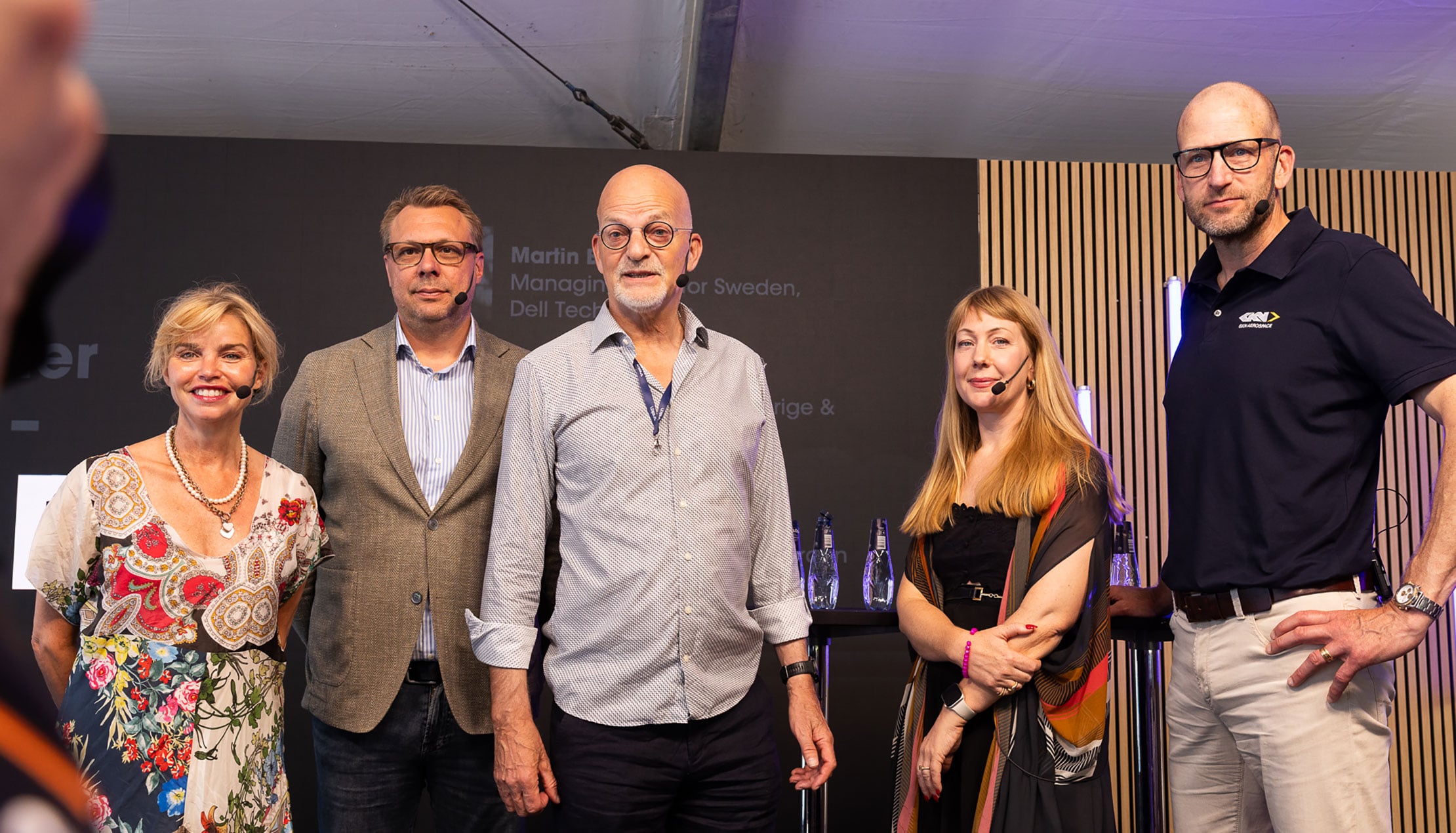 Alla paneldeltagarna står på scenen och tittar in i kameran