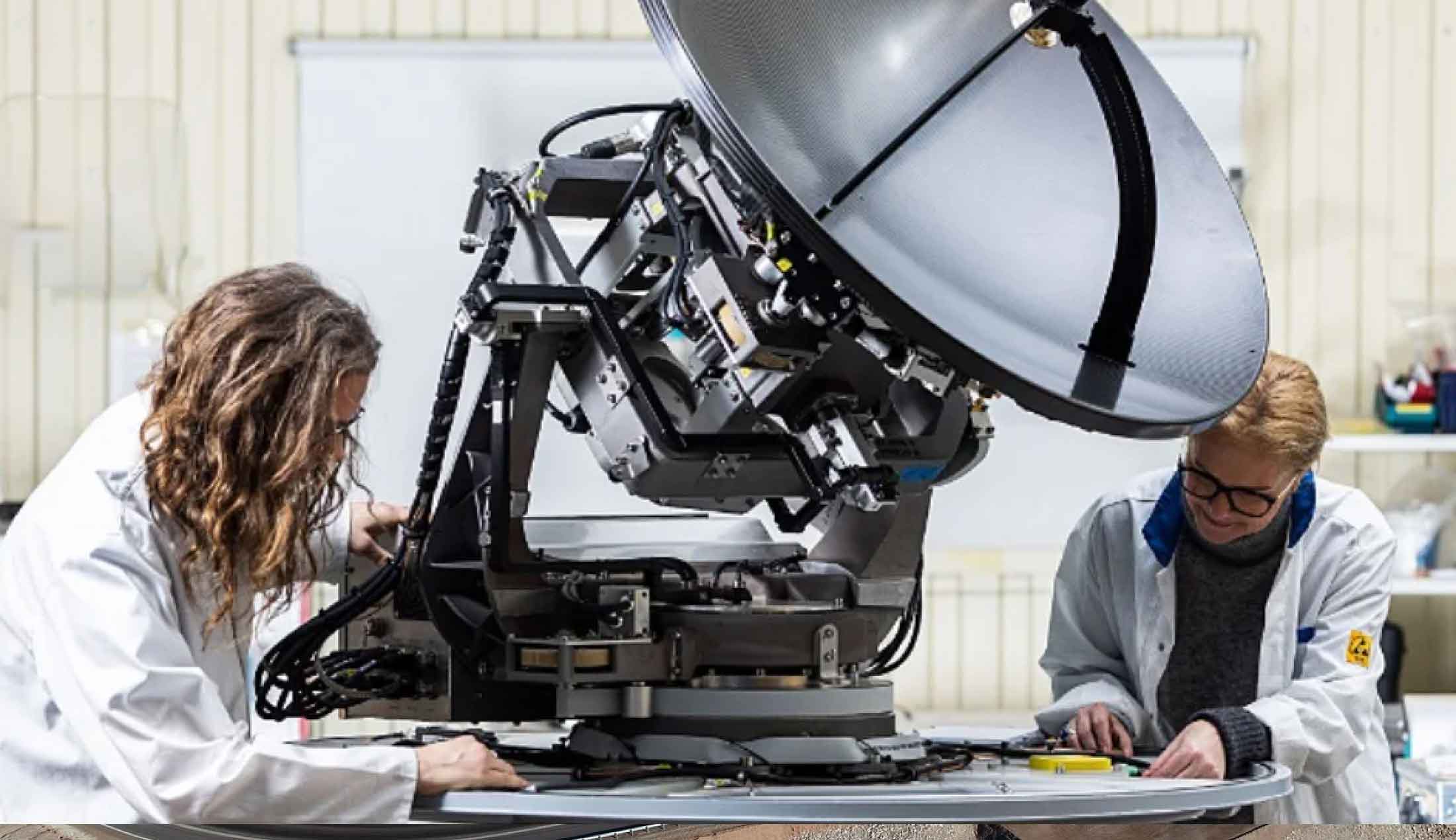 Två personer i labbrockar arbetar med en antenn