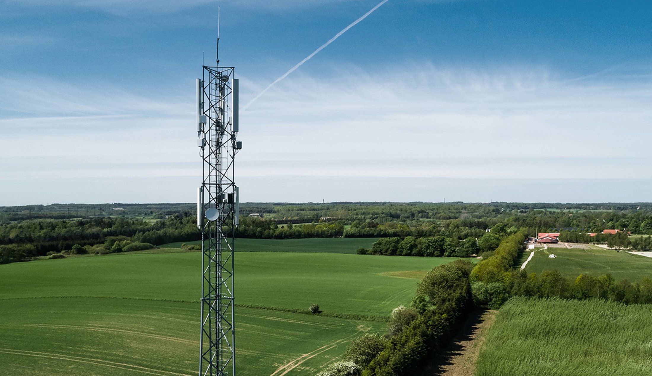 A high radio tower in a lush landscape.