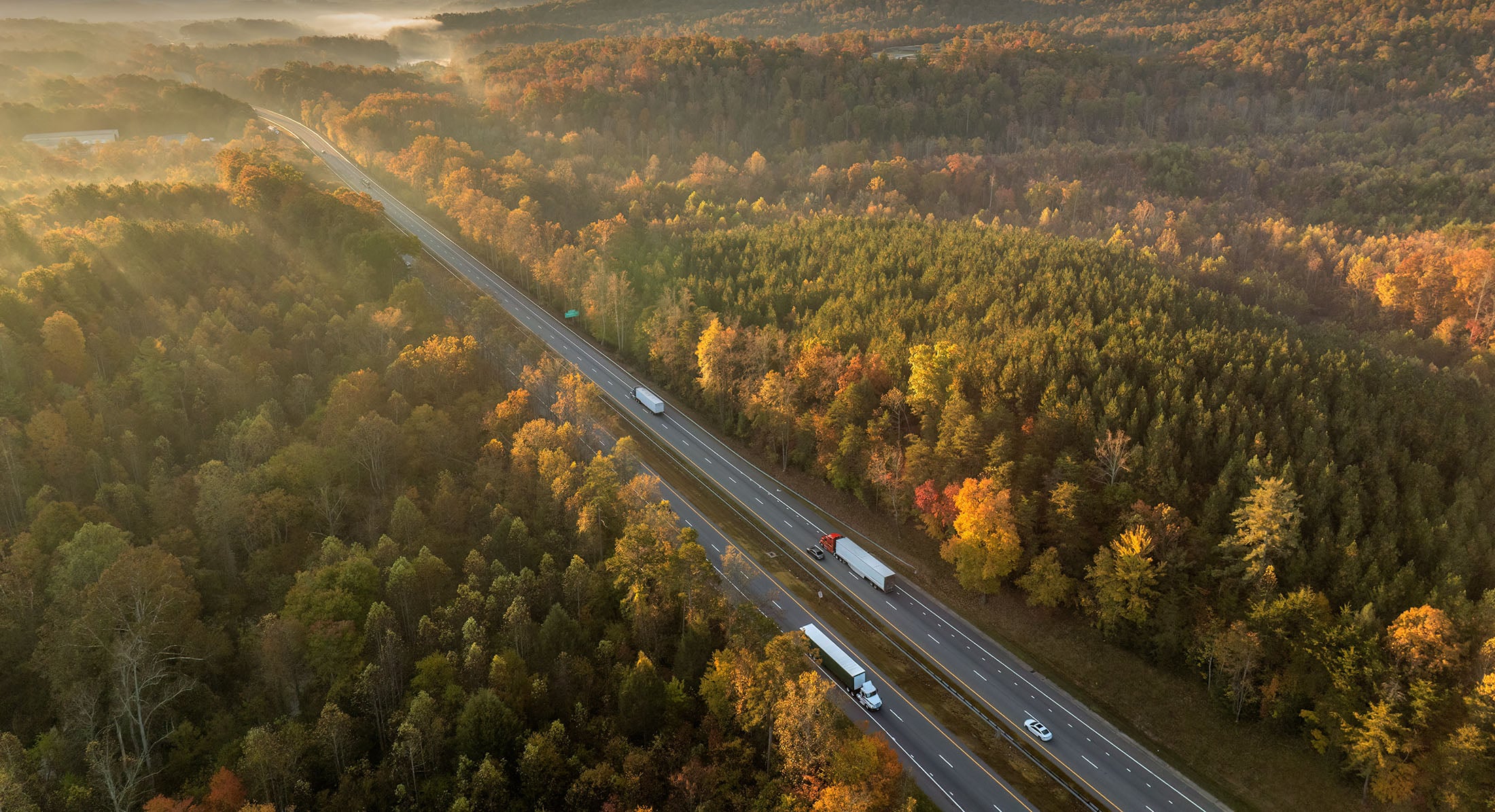 Lastbilar på motorväg i höstlandskap