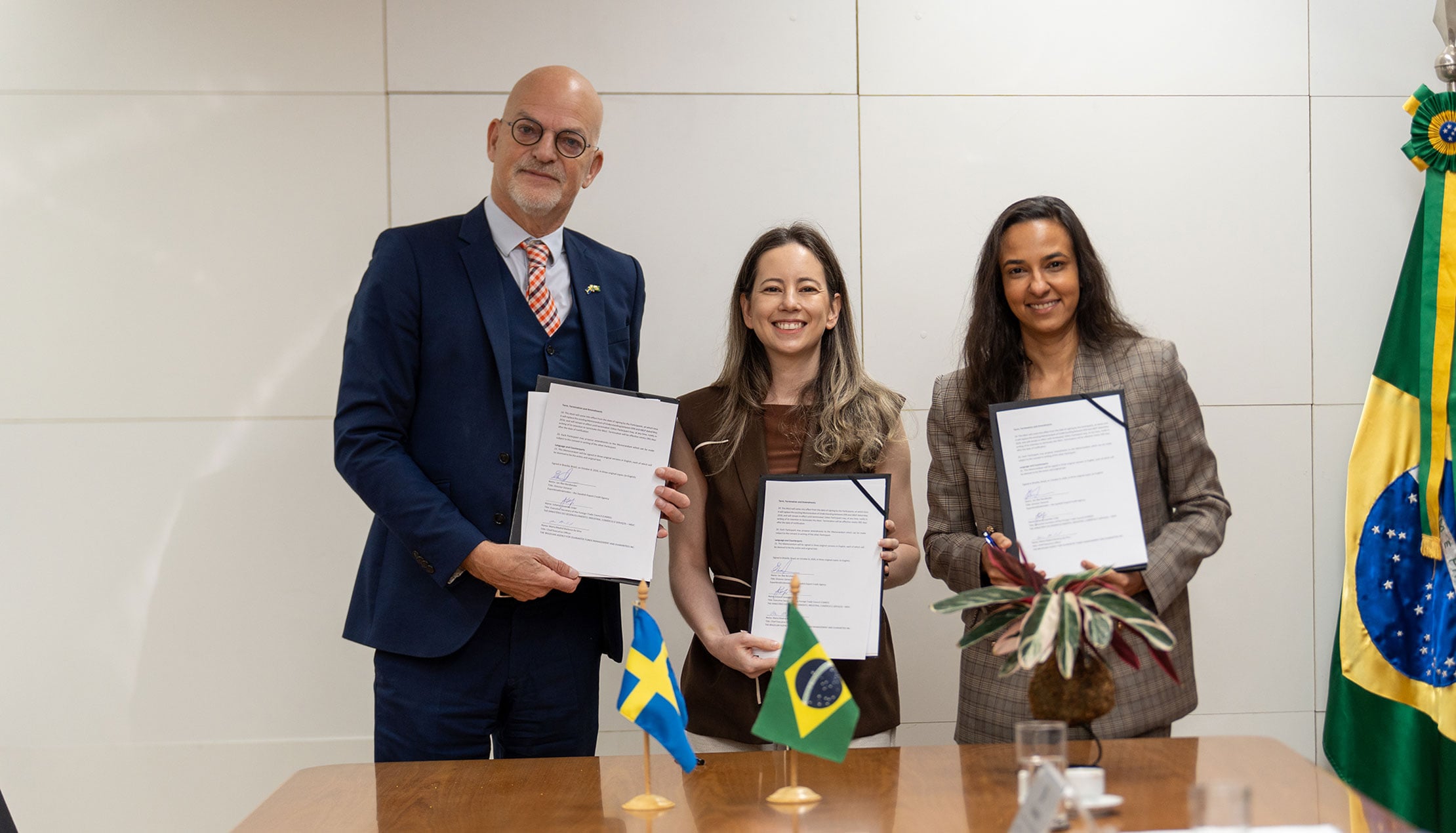 The persons signing the MoU holding up the documents to the camera.