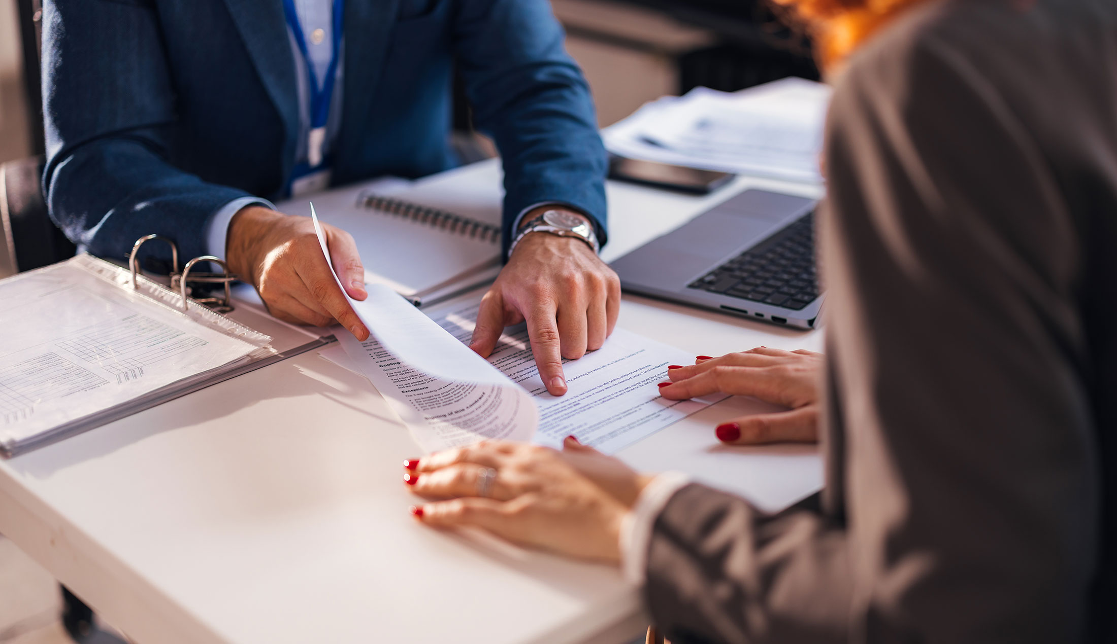 Close-up of two people working on a document lying on the table between them.