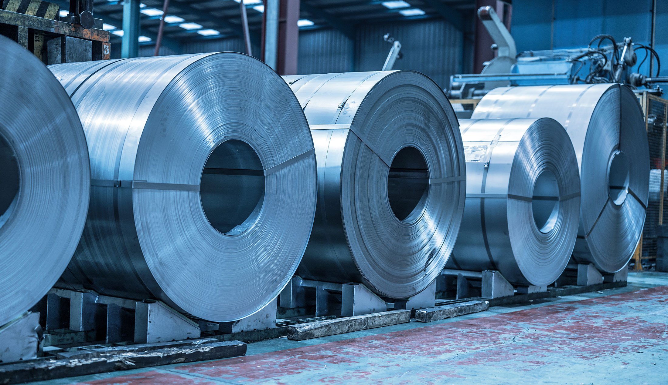 Large metal coils stored in a warehouse.