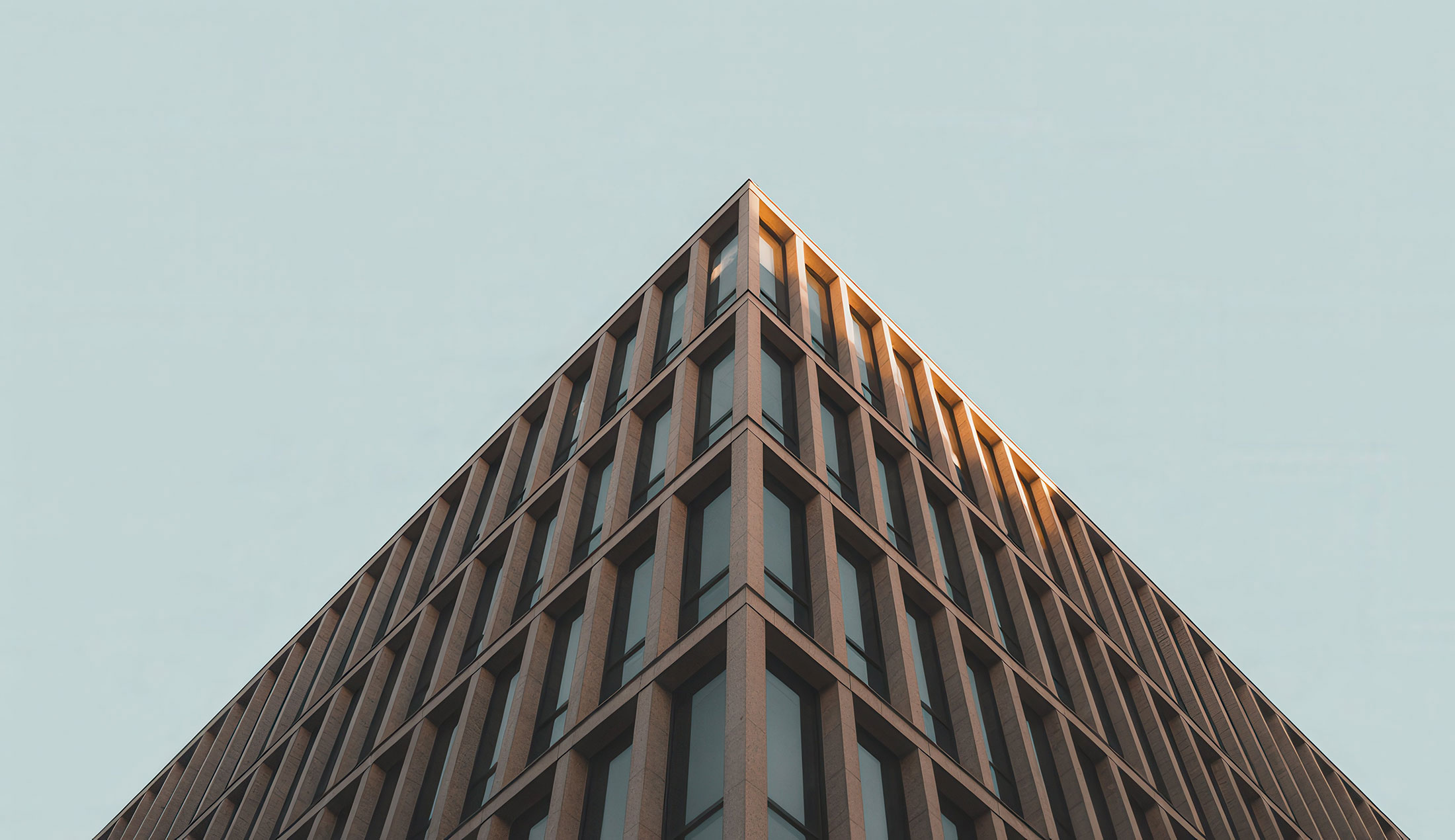 The corner of a modern office building seen from a low-angle perspective. The image is AI-generated.