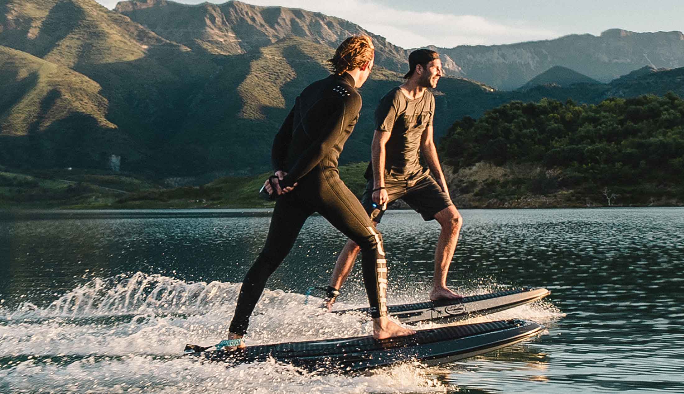 Två män som surfar på elektriska surfbrädor på vatten.