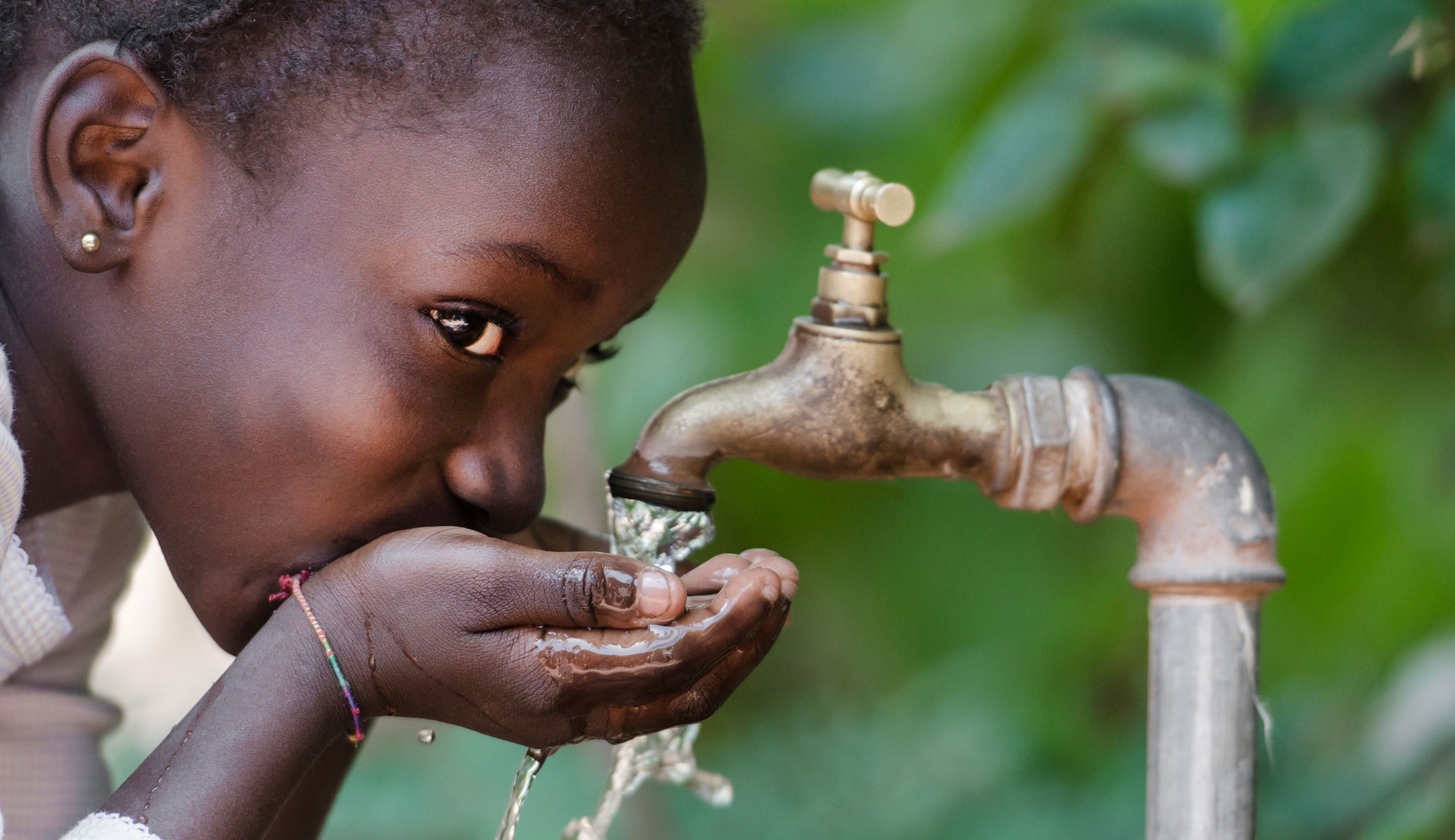 A child drinking water from a tap